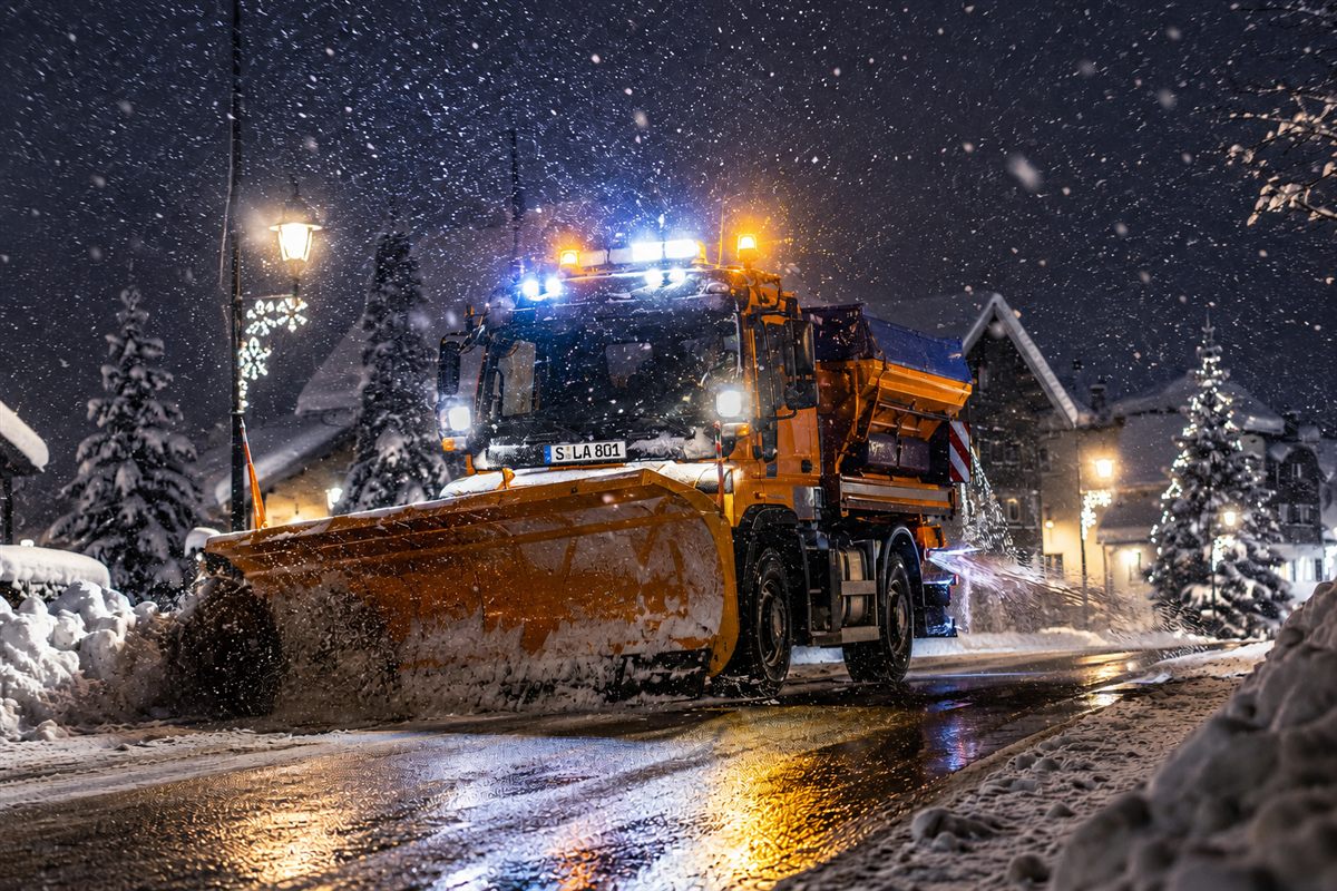 Winterdienst-Fahrzeug räumt und streut nachts eine verschneite Straße