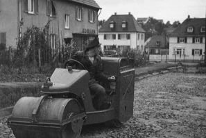 Historische Aufnahme von 1959: Fahrer auf einer Straßenwalze in einer Wohnstraße